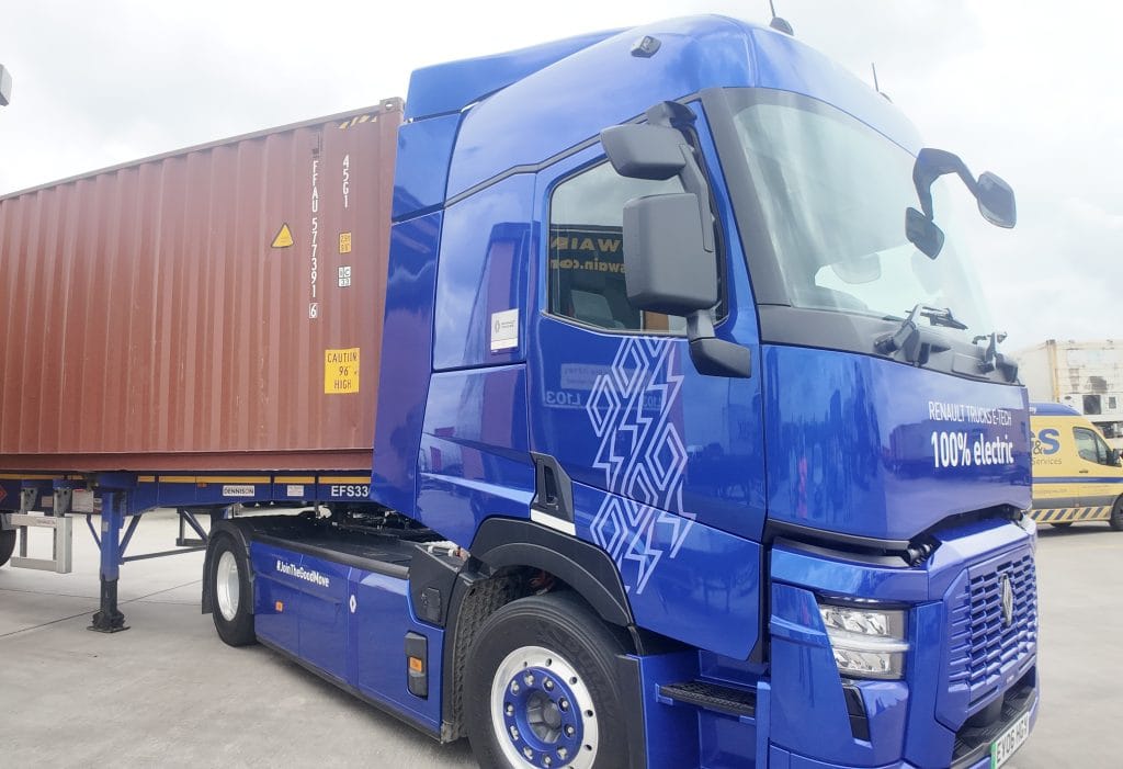 Blue Renault Trucks E-Tech 100% electric HGV hauling a container on a Dennison trailer at a logistics site